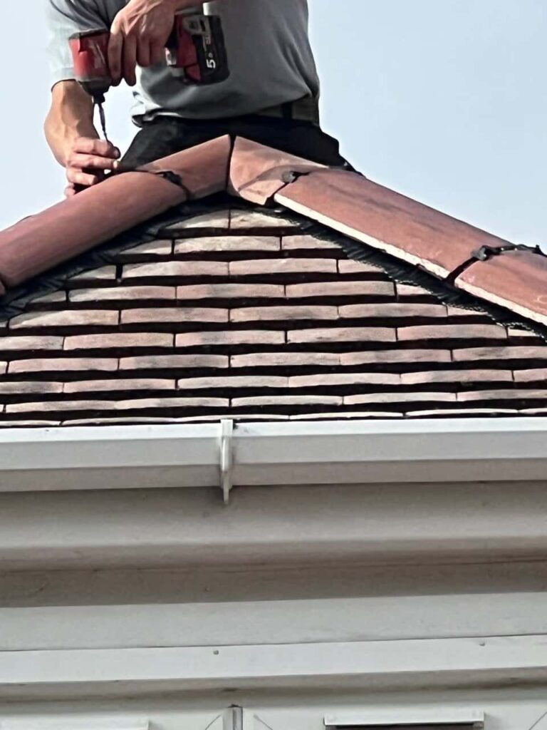 This is a photo of one of the operatives of LJ Roofing Witney installing new ridge tiles