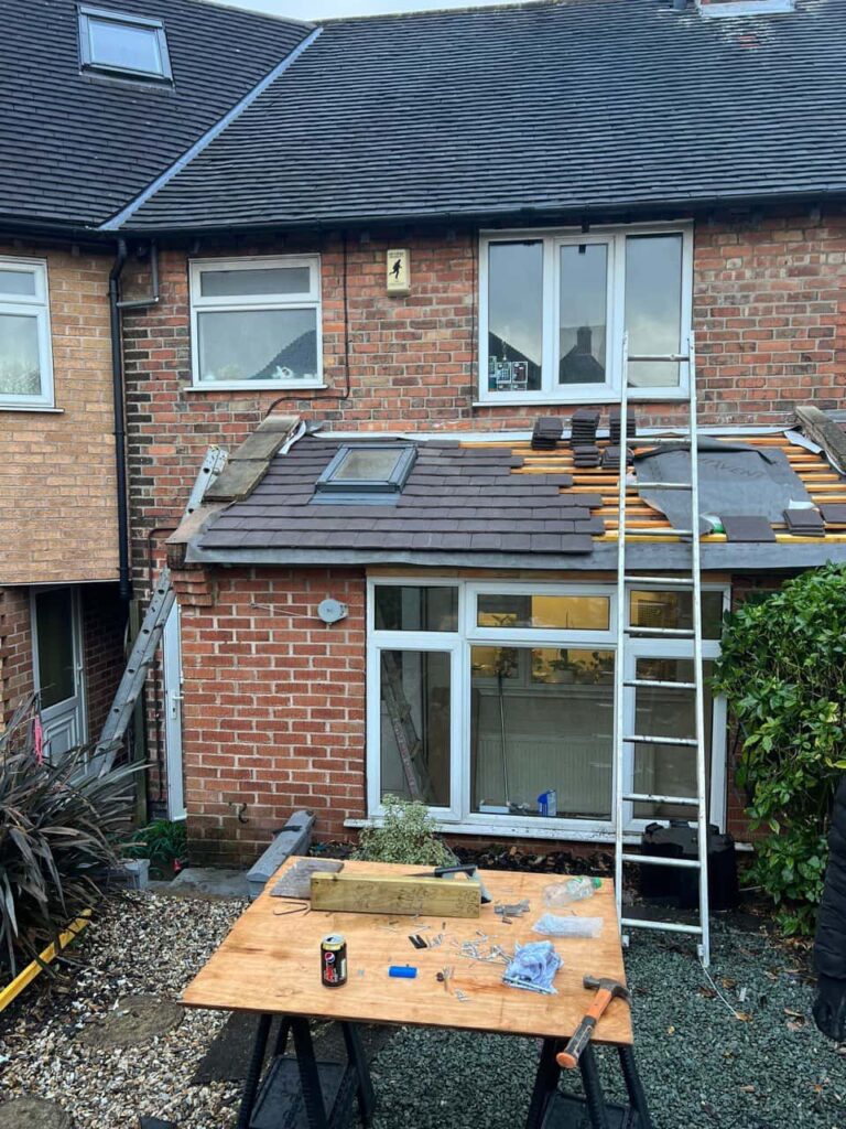 This is a photo of a roof extension that is having new roof tiles installed. This is a photo taken from the roof ridge looking down a tiled pitched roof on to a flat roof. Works carried out by LJ Roofing Witney
